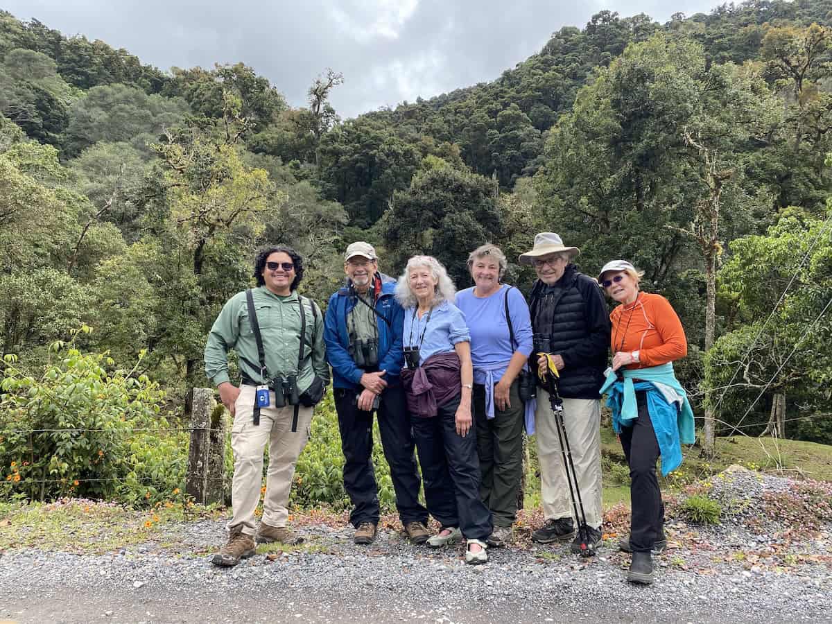 A group of Oceanic Society travelers pose with their guide Ernesto Ocampo in front of lush Costa Rican forest.
