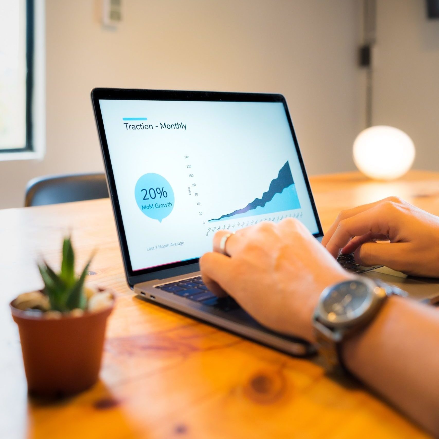 hands typing on laptop with a plant beside it